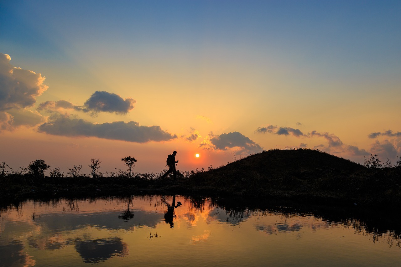 Percorso panoramico al tramonto, con silhouette di colline e cielo colorato.
