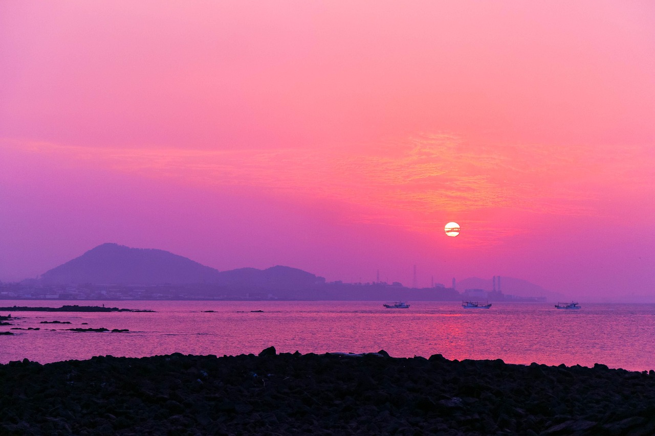 Punto panoramico con vista su tramonto rosa, cielo sfumato di tonalità calde e silhouette di montagne.