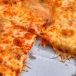 Pizza fredda il giorno dopo, con fette disposte su un piatto, evidenziando la consistenza e i colori.