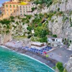 Spiaggia di Furore con il ponte che sovrasta i bagnanti e le acque cristalline.