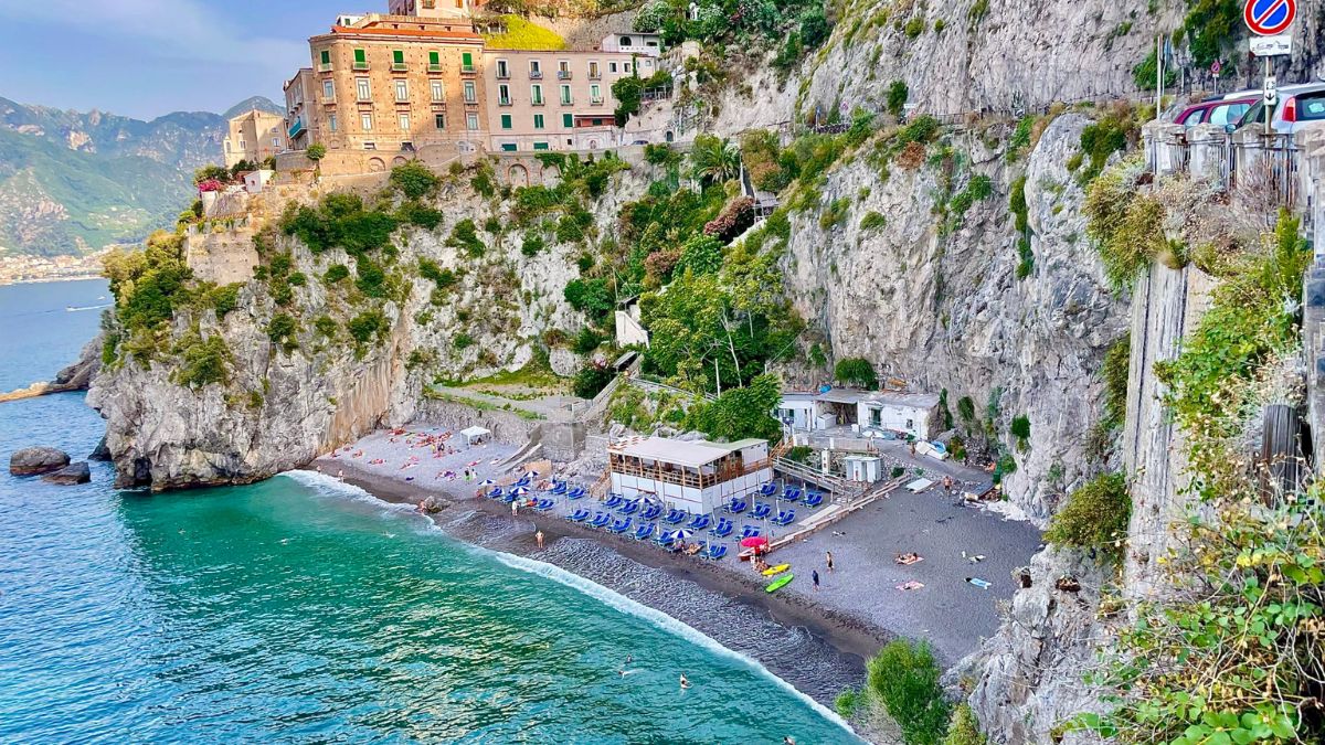 Spiaggia di Furore con il ponte che sovrasta i bagnanti e le acque cristalline.