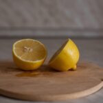 Tagliere in legno con limone e sale grosso, pronto per una pulizia naturale e igienizzante.